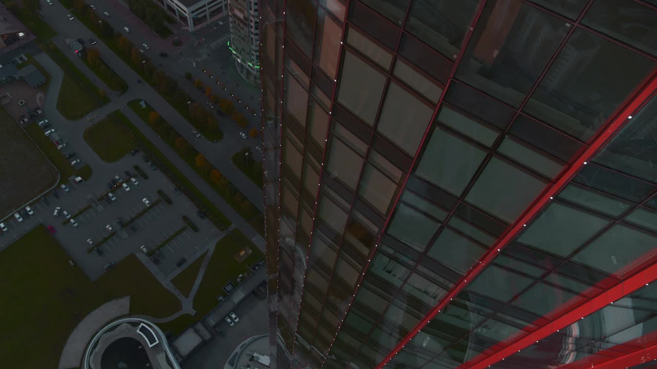 现代玻璃办公摩天大楼的鸟瞰图，窗外反射出城市景观。资料片。在一个夏日的夜晚飞过这座现代化的城市视频素材