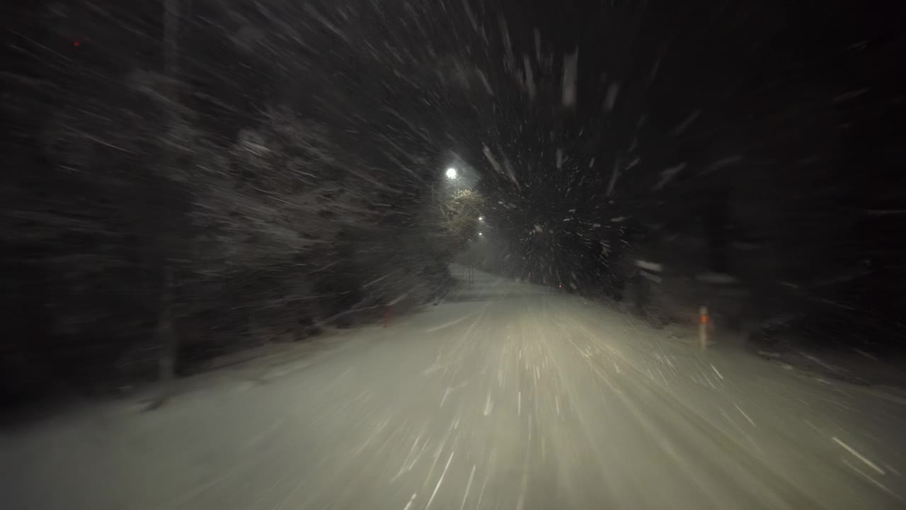 在暴风雪中的冬日夜晚的道路上视频素材