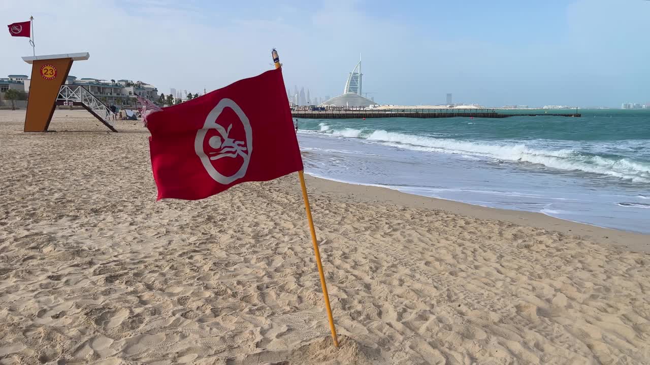 在阿联酋迪拜的海滩上，一面红色的警告旗迎风飘扬。海上有风暴，不能游泳视频素材