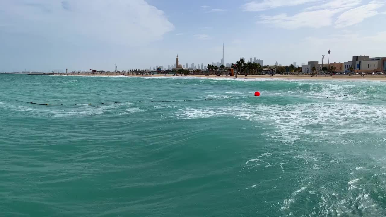 阿联酋迪拜海岸附近海域的巨浪。从大海到海滩，背景是摩天大楼视频素材