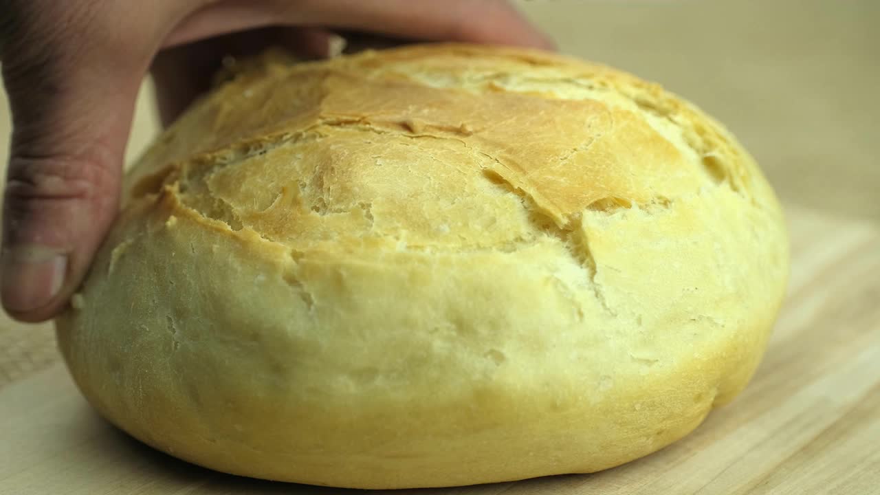 用白面粉制成的新鲜出炉的白面包，厨师的手正在切面包。视频素材