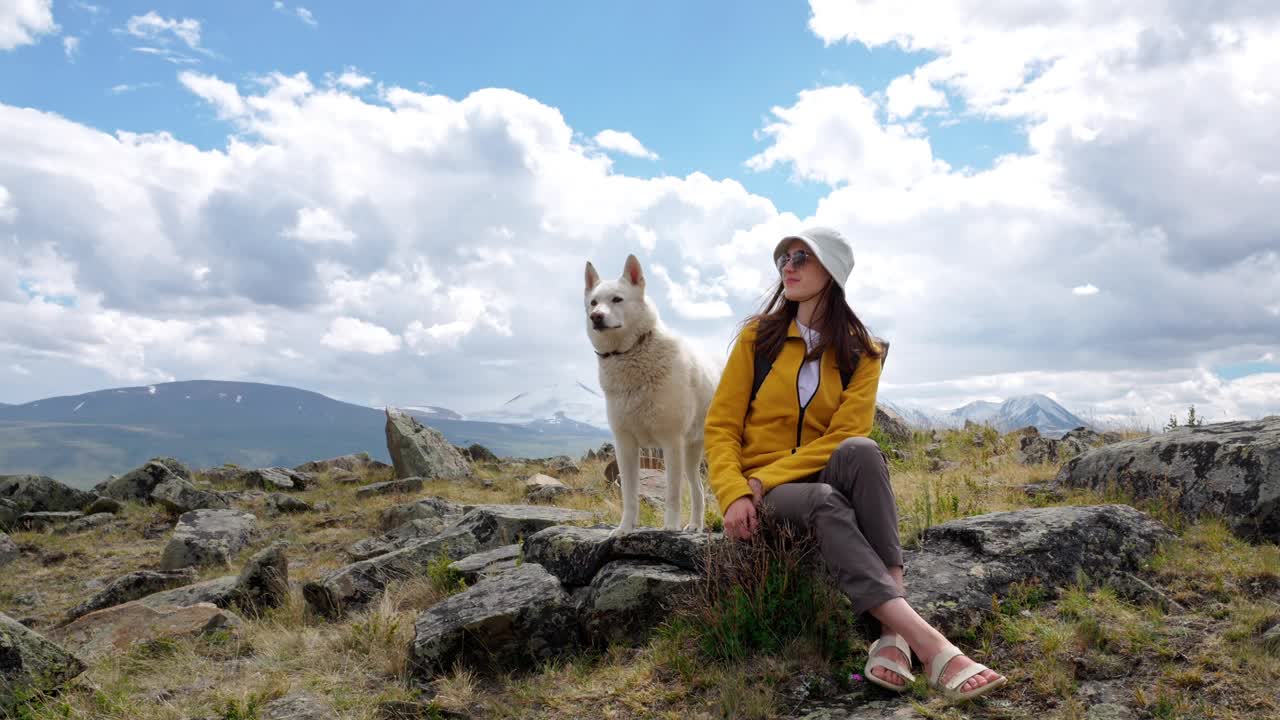 徒步旅行的女人，可爱的宠物狗坐在岩石区在风景秀丽，山景视频下载