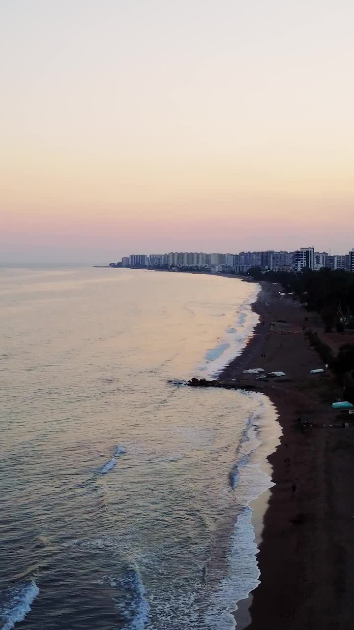 无人机展示日落时的海岸景观。傍晚的光线增强了沿海景观的美丽。宁静的海岸景观，在这里大海与繁华的小镇相遇视频素材