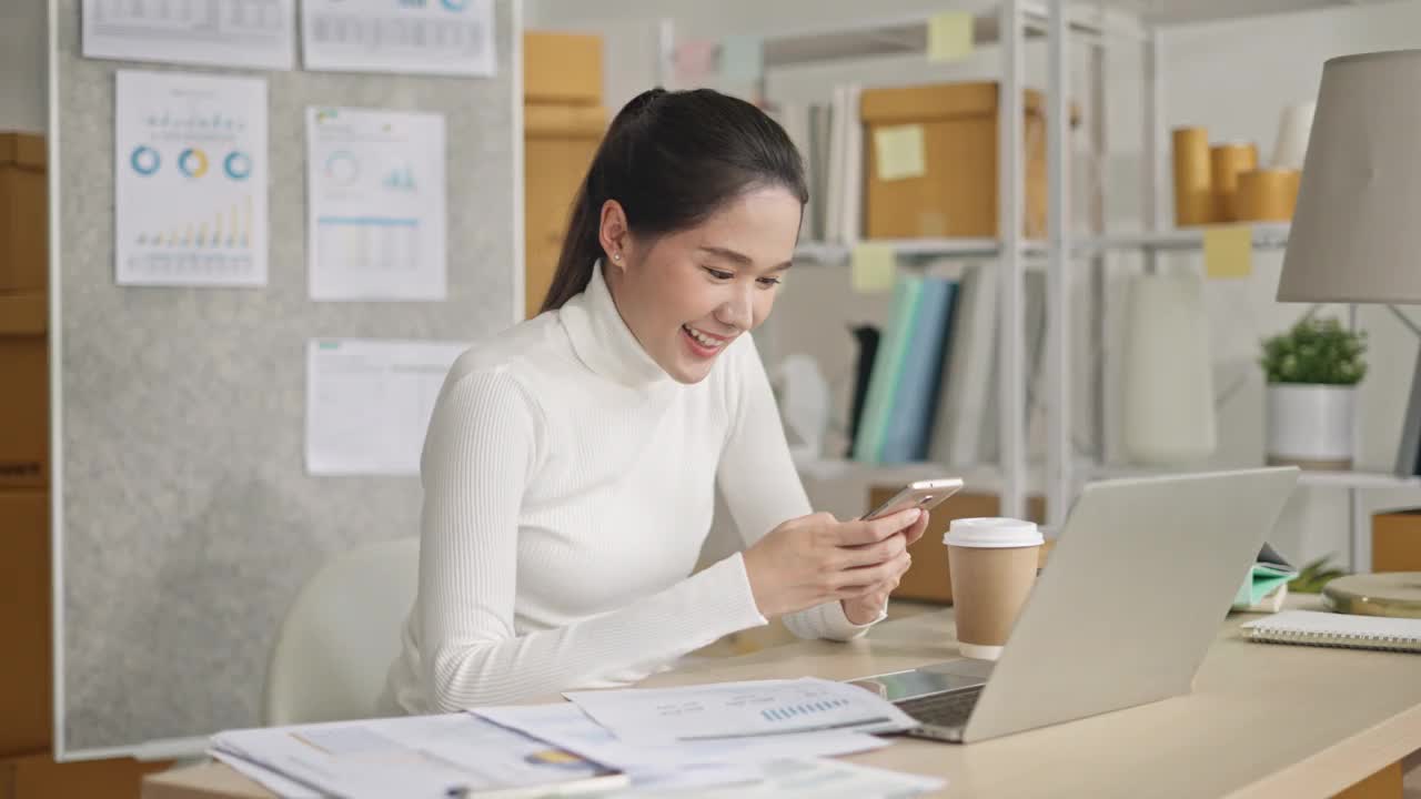 亚洲自由职业聪明的商务女性休闲装使用智能手机在家办公视频下载