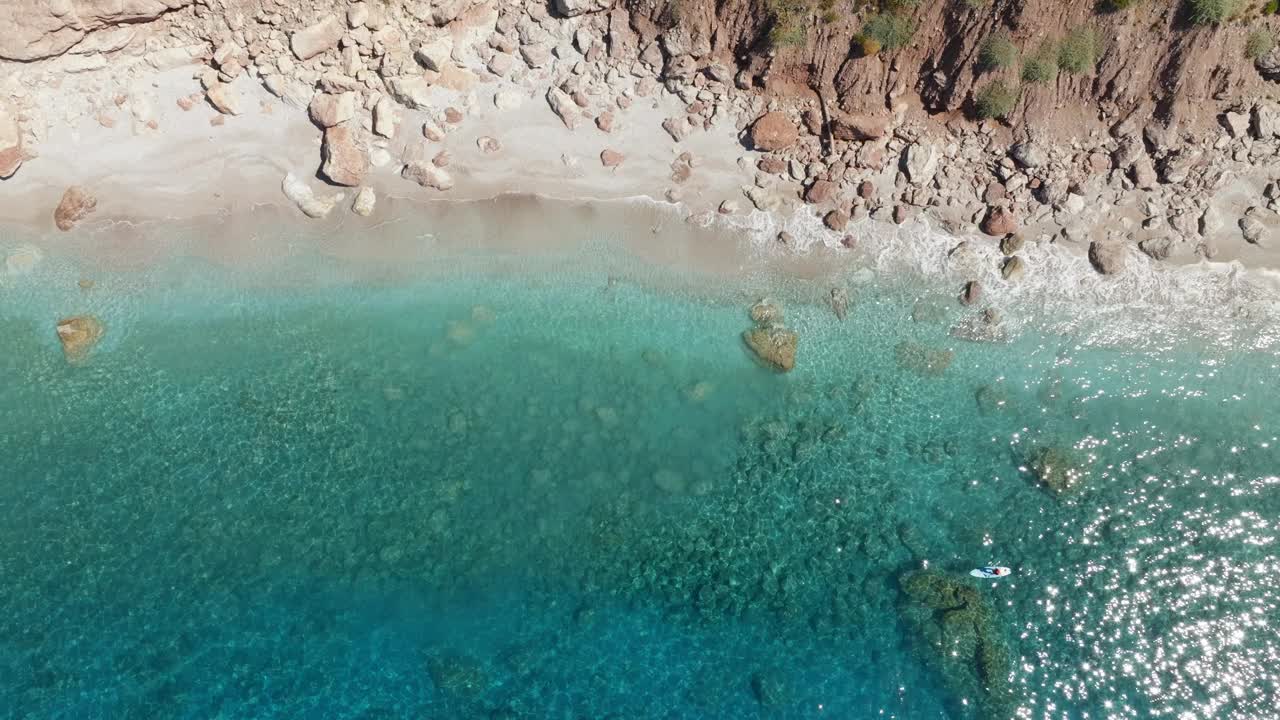 男子在站立式桨板上游泳，俯瞰海景。视频素材