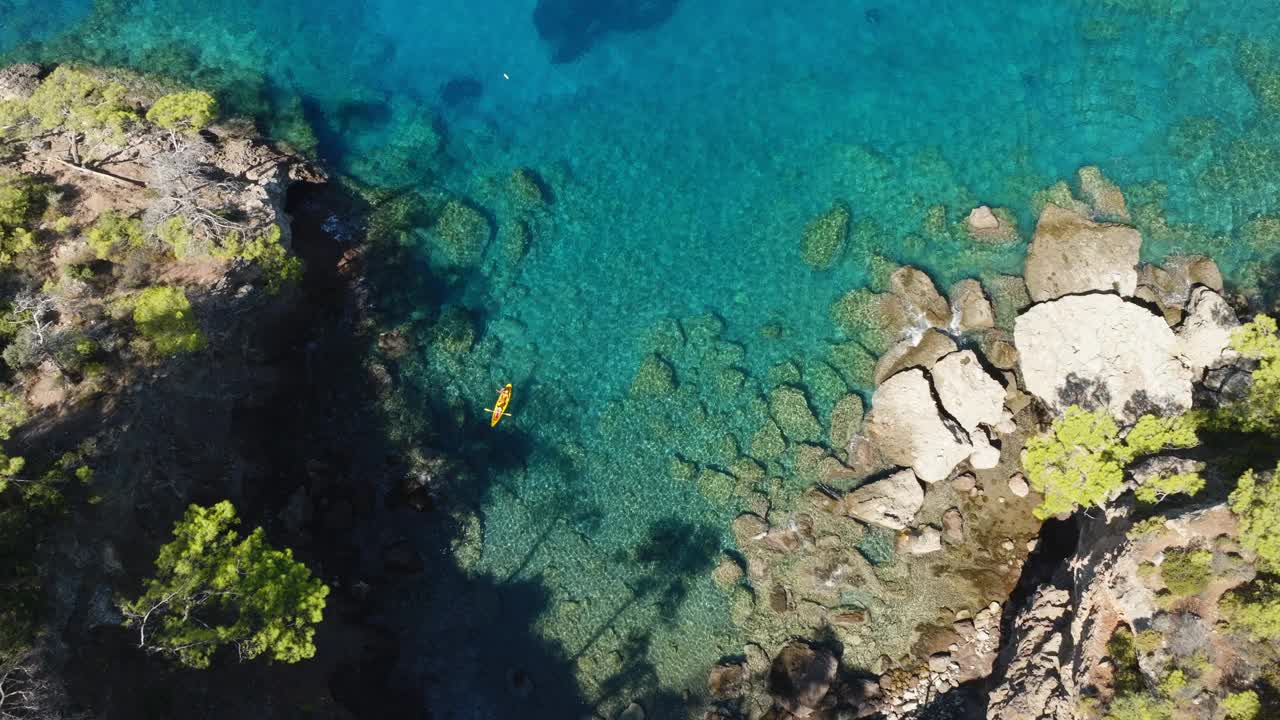 一男一女在阳光明媚的日子里沿着海岸线划着他们的海上皮艇。无人机的视角。视频素材