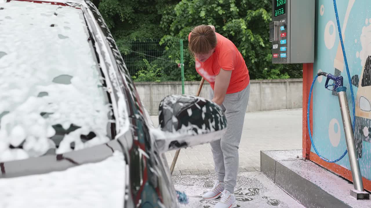 这位妇女在自助洗车店洗车。视频素材