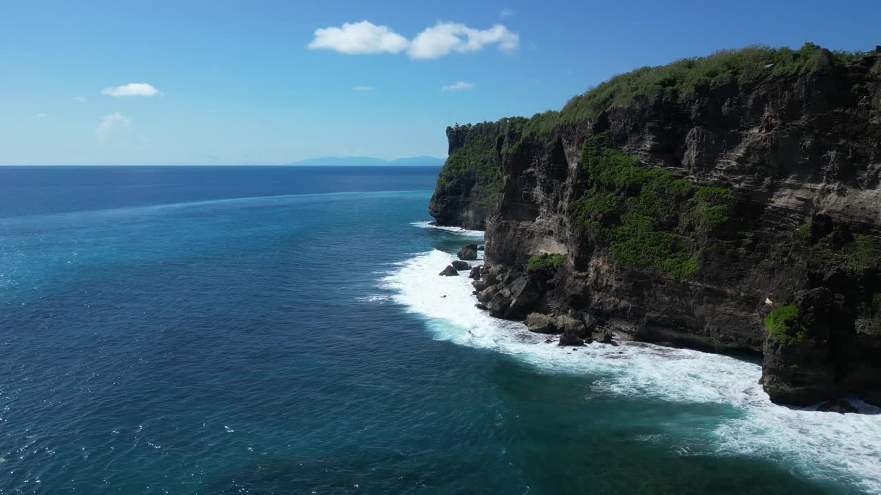 在炎热的夏日，巴厘岛乌鲁瓦图的悬崖上，海浪拍打着岩石，空中。视频素材