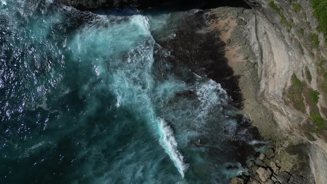 在炎热的夏天，鸟瞰清澈的海浪涌向巴厘岛南部的海滩。视频素材