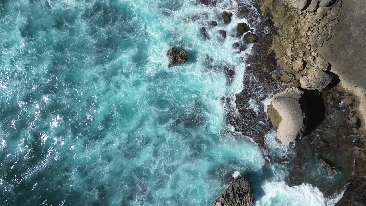 从鸟瞰美丽明亮的蓝色海水与海浪撞击，在巴厘岛，印度尼西亚。天线。视频素材