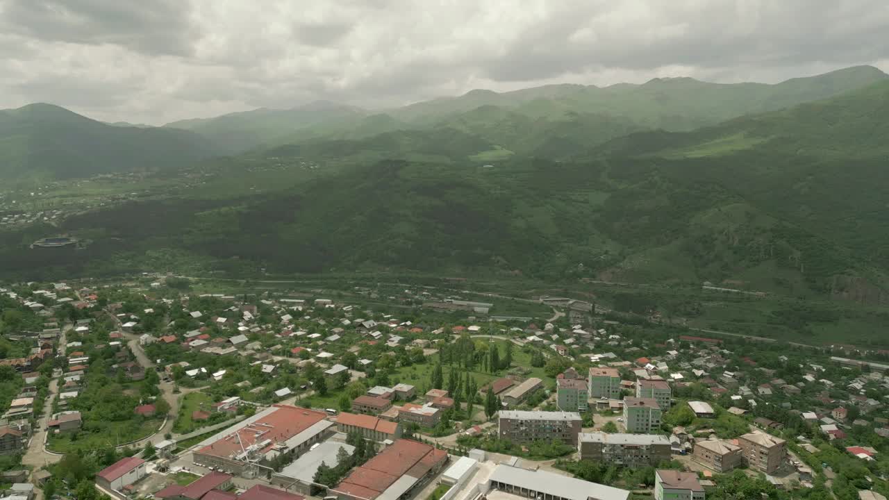 这座城市的房屋被树木繁茂的高山和悬崖所环绕。无人机视频视频素材