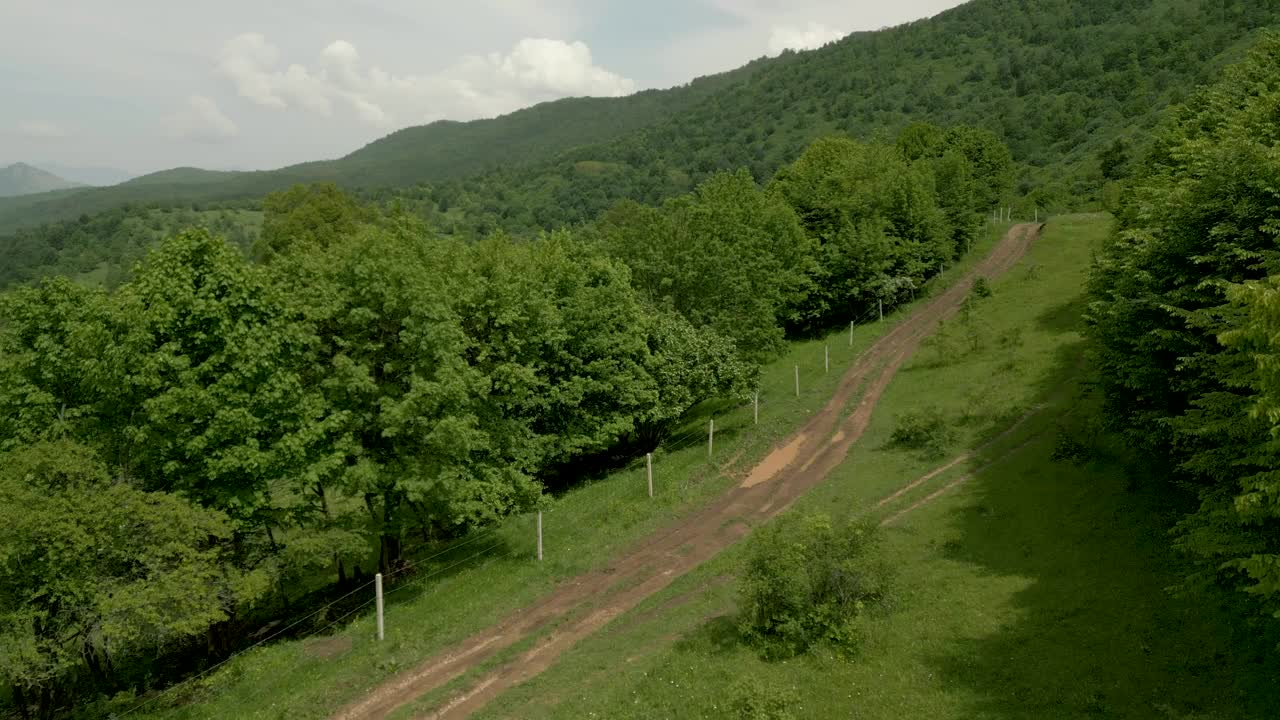 快速飞越乡村道路，转向小镇树木繁茂的山区无人机视频视频下载