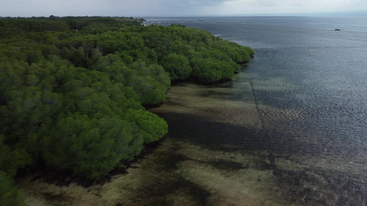 鸟瞰巴厘岛努沙伦博根旅游岛美丽的海岸线，在一次令人兴奋的印度尼西亚之旅中，可以看到森林、码头上的船只和建筑物视频素材