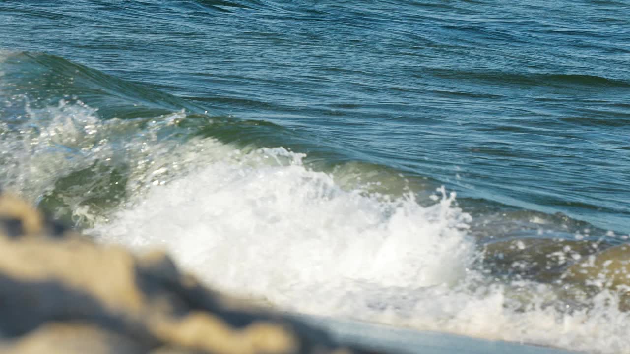 海浪轻轻拍打着岩石海岸线的特写镜头，海水清澈湛蓝。视频素材