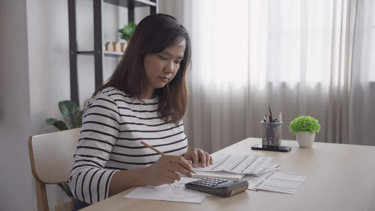 用计算器和便签本分析和计算家庭财务账单视频素材