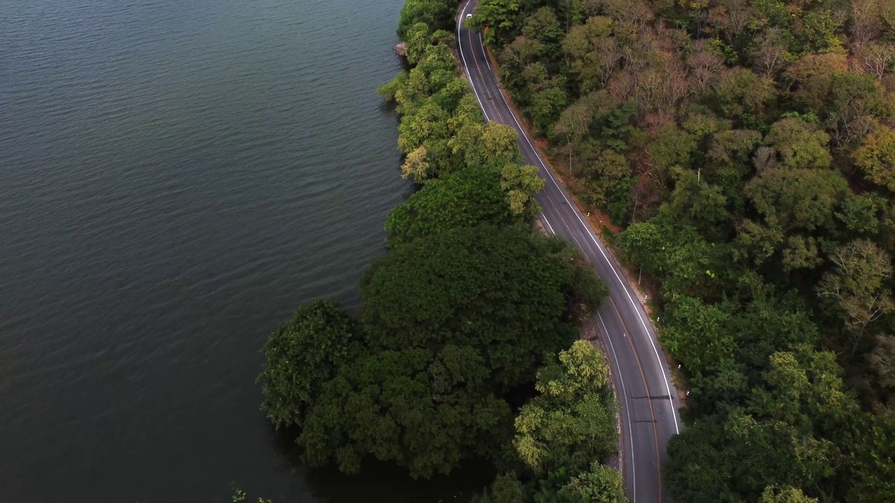 鸟瞰图的汽车行驶在道路之间的水和森林视频素材