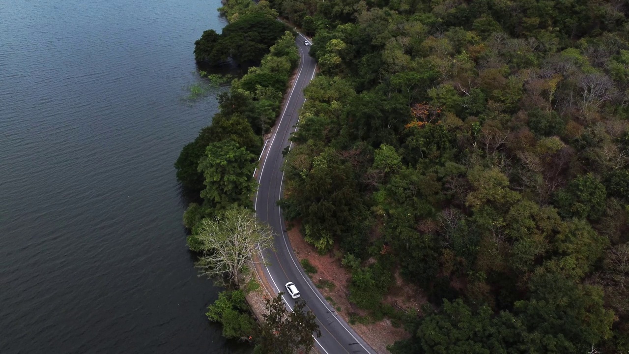 鸟瞰图的汽车行驶在道路之间的水和森林视频下载