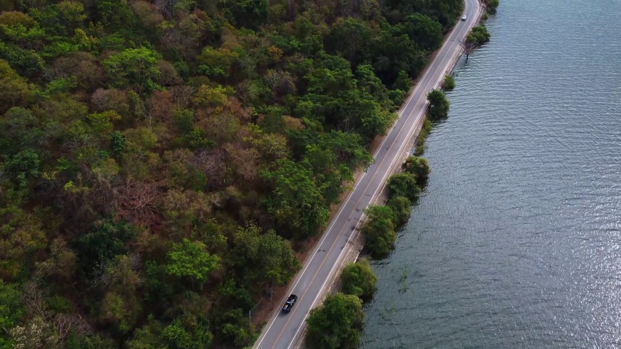 鸟瞰图的汽车行驶在道路之间的水和森林视频下载