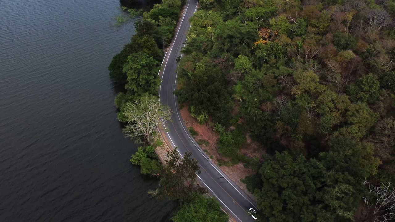 鸟瞰图的汽车行驶在道路之间的水和森林视频素材