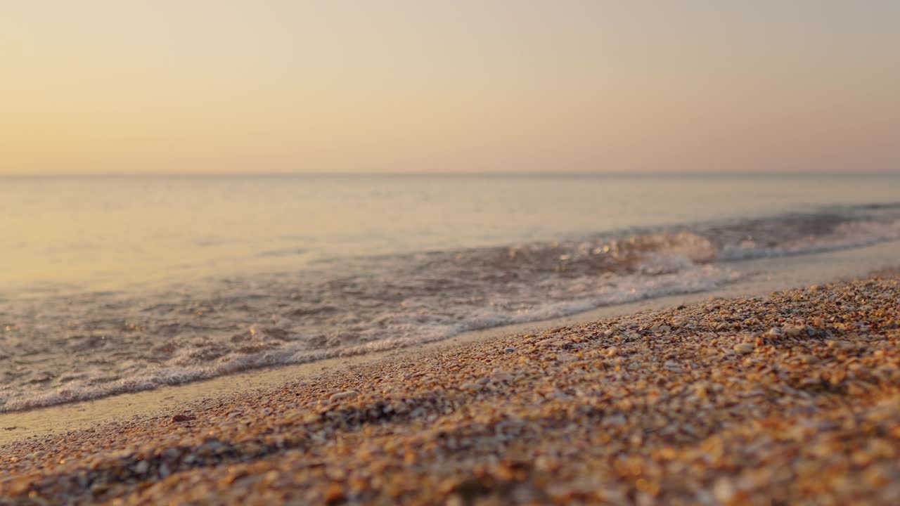 美丽的风景与明亮的金色波浪在日落的海滩上。视频素材