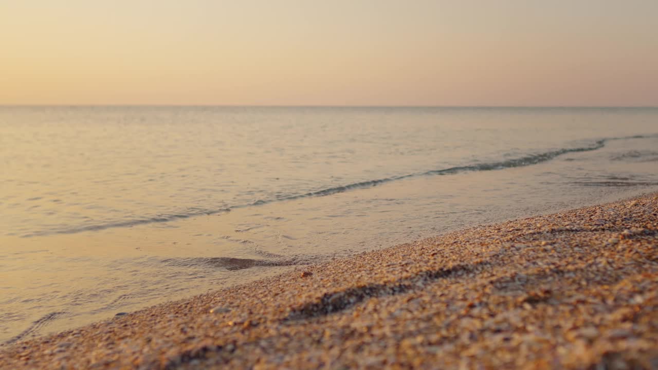 日落时黑海海滩上明亮的金色波浪。视频素材