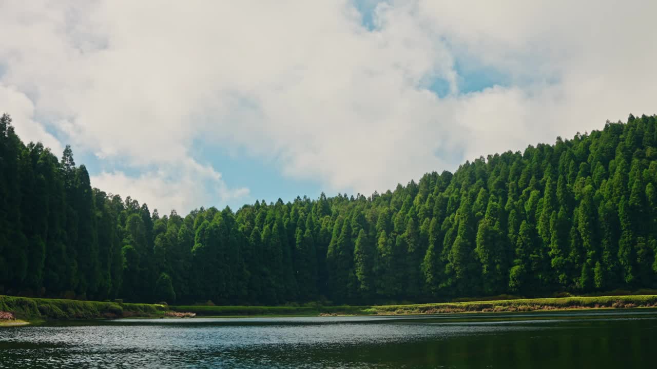 时间在高山湖泊上流逝，周围是绿色的高松。风景如画的湖景。高旅行云的云。视频素材