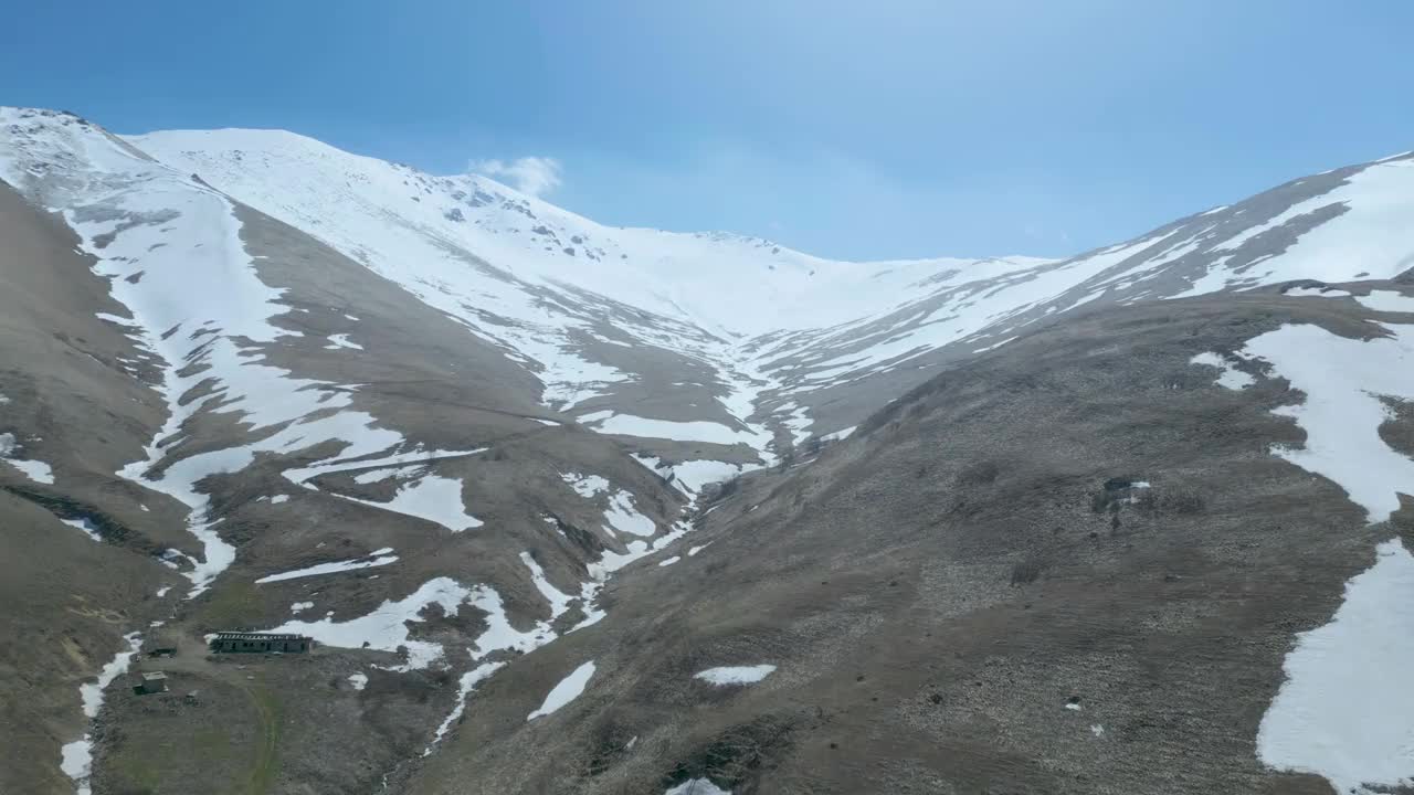 高空鸟瞰图，蓝天下覆盖着白雪的高山视频素材