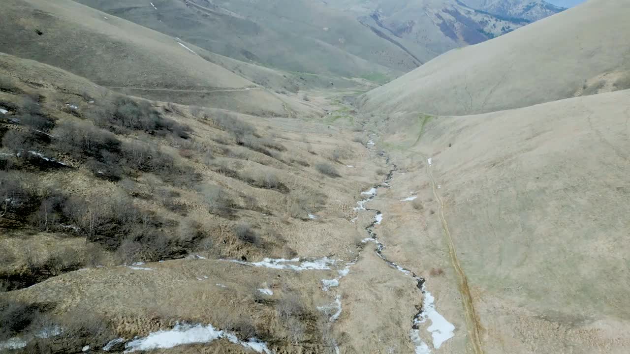 鸟瞰蜿蜒的山河峡谷。沿着河岸和树木的雪融化了视频下载