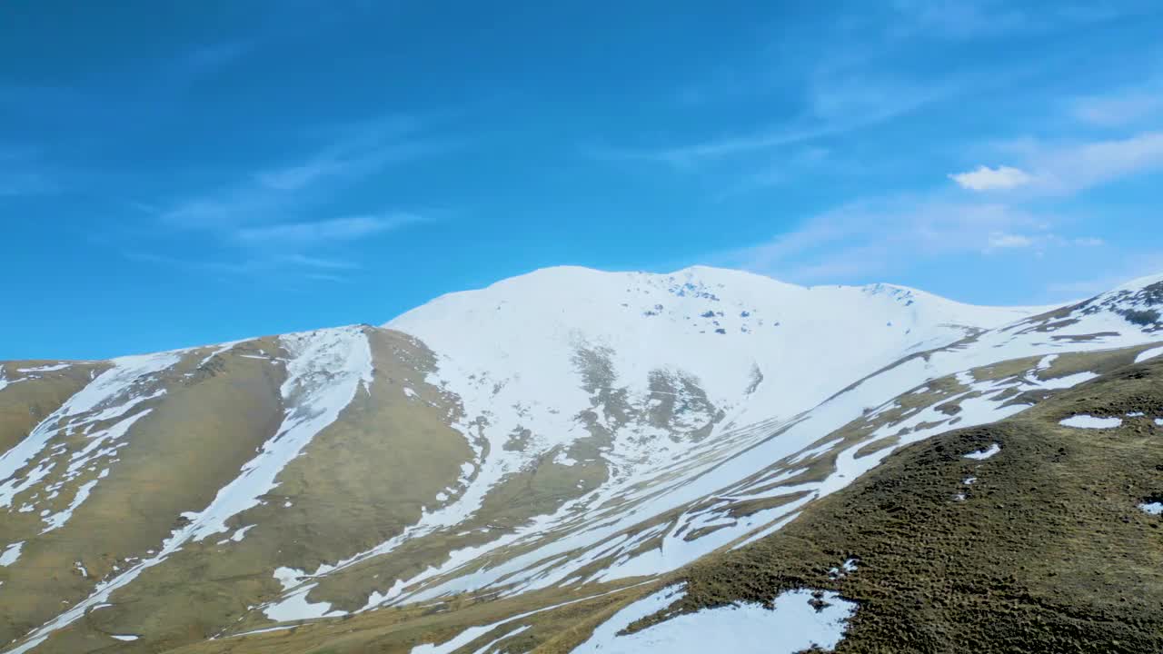 高空鸟瞰图，蓝天下覆盖着白雪的高山视频下载