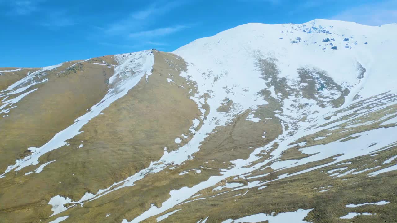 高空鸟瞰图，蓝天下覆盖着白雪的高山视频下载