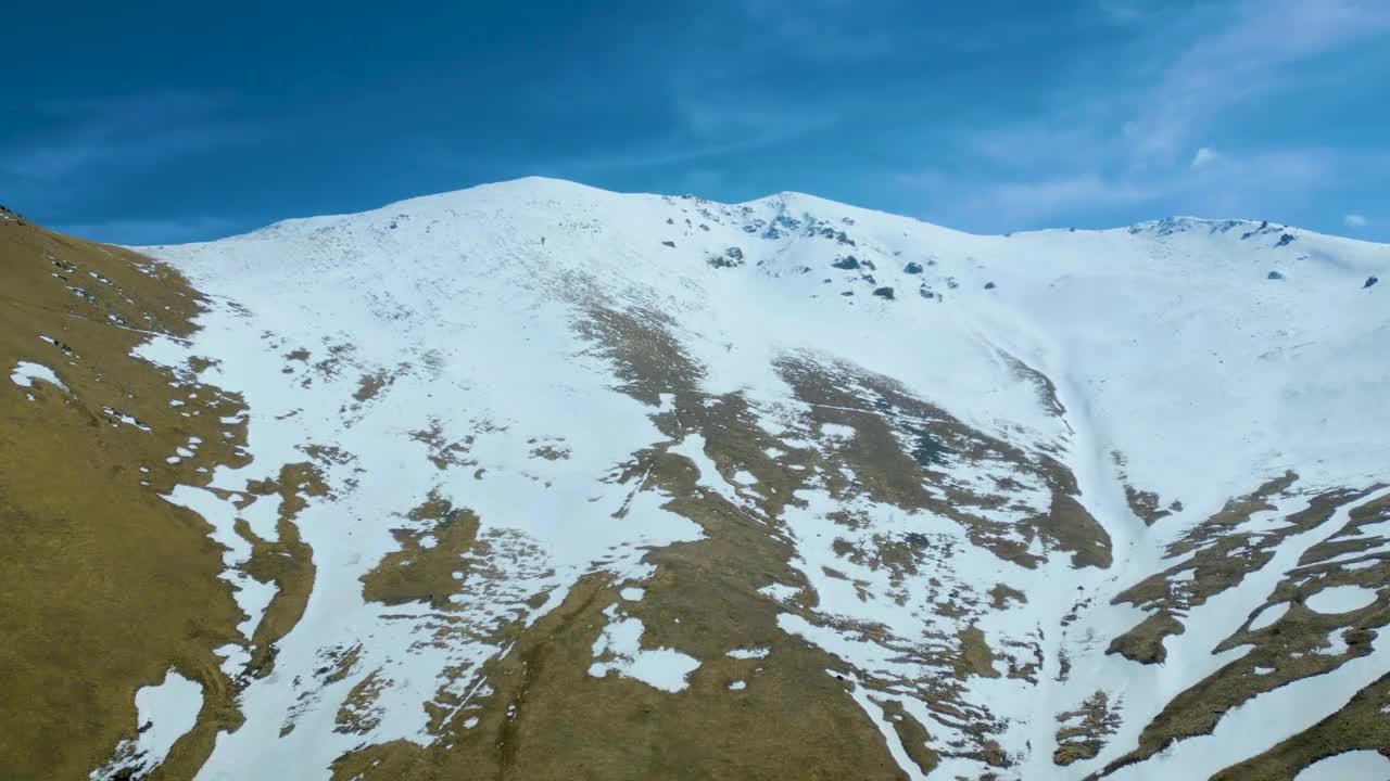 高空鸟瞰图，蓝天下覆盖着白雪的高山视频素材