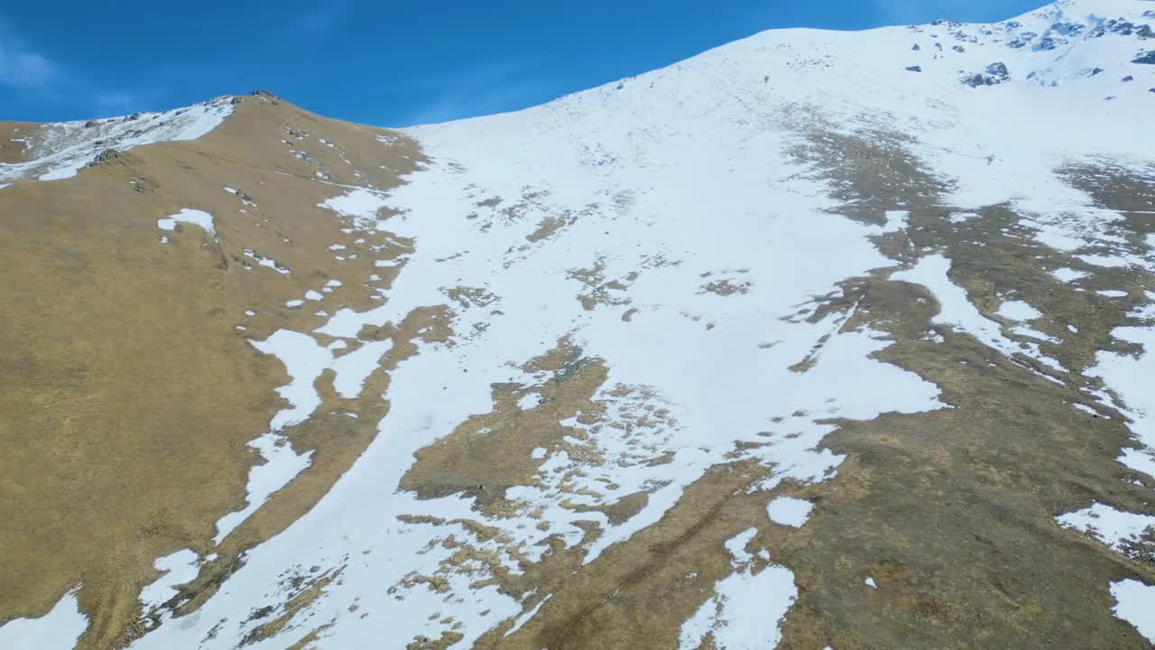 高空鸟瞰图，蓝天下覆盖着白雪的高山视频素材