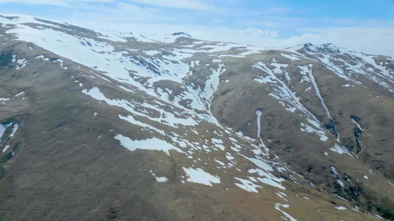 高空鸟瞰图，蓝天下覆盖着白雪的高山视频下载