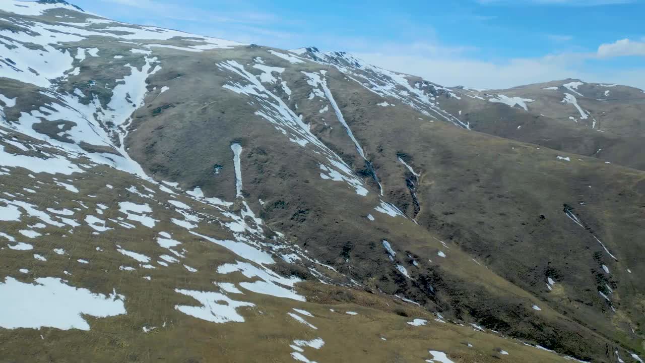 高空鸟瞰图，蓝天下覆盖着白雪的高山视频素材