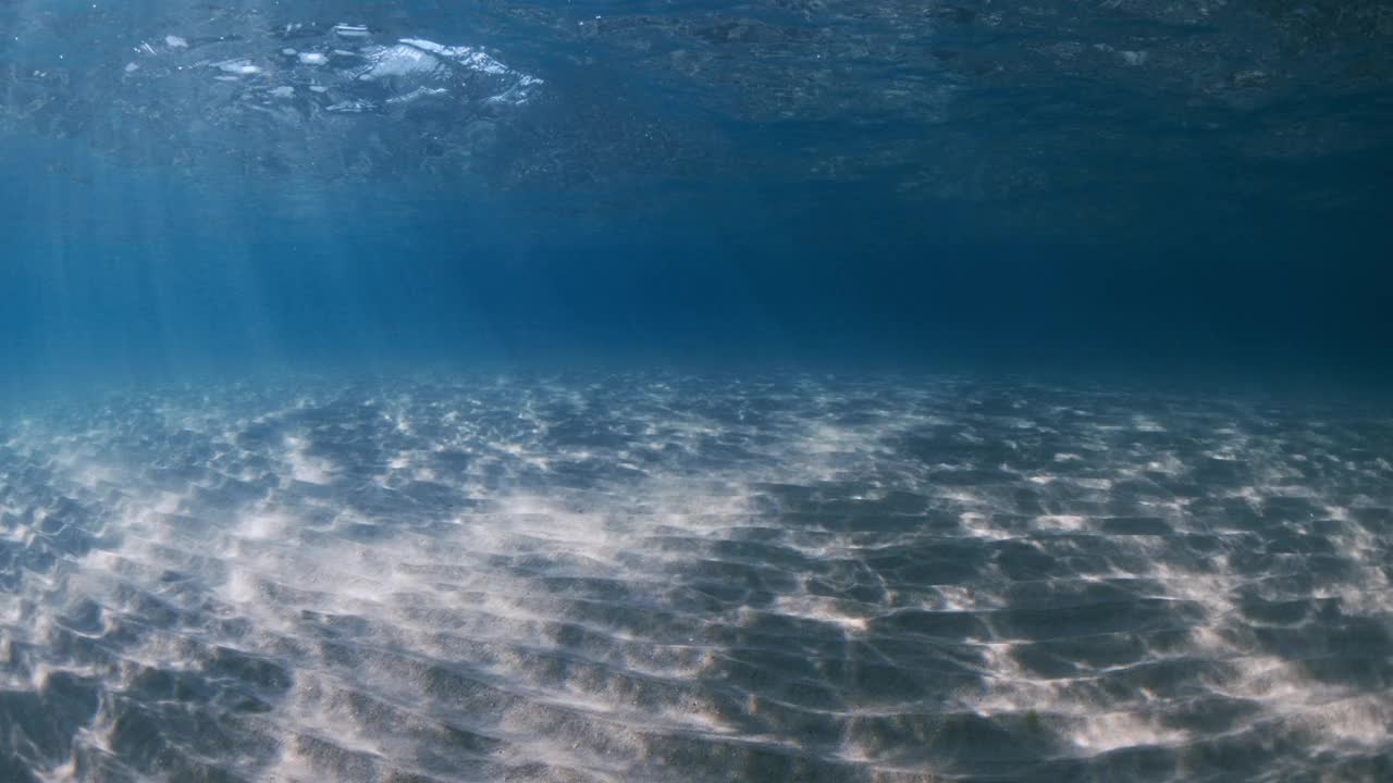 透明的海洋，阳光，沙质海底和水下波浪视频素材