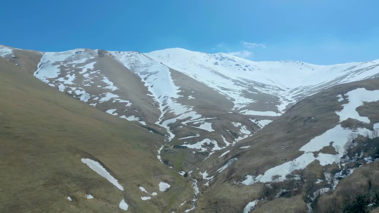 高空鸟瞰图，蓝天下覆盖着白雪的高山视频素材