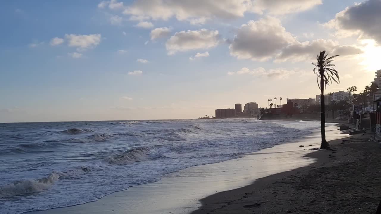 在一个寒冷的冬日，西班牙太阳海岸的贝纳尔马德纳海滩上，海浪拍打着海滩的短视频。视频素材