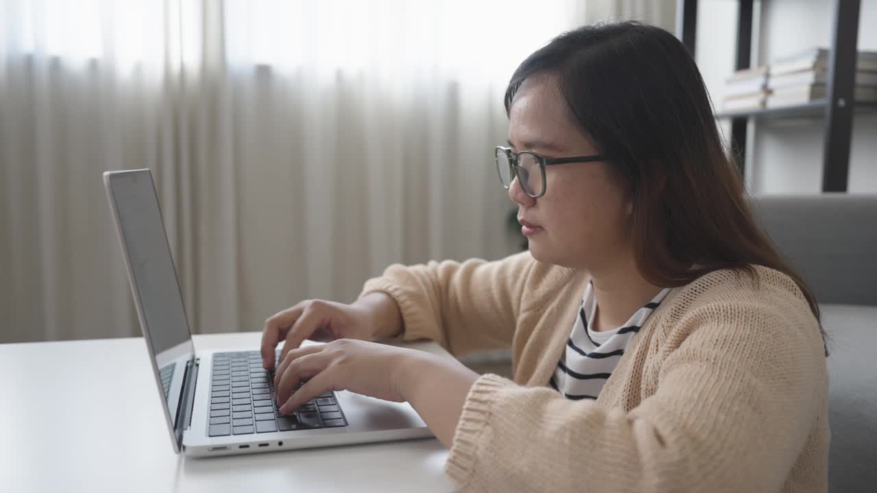 亚洲女人坐在地板上用笔记本电脑在客厅工作视频素材