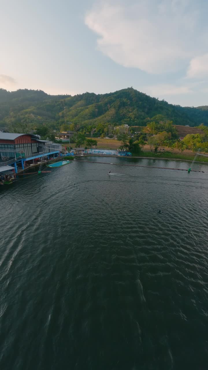 垂直视频。滑水男子骑水手击掌欢呼倒下的朋友视频素材