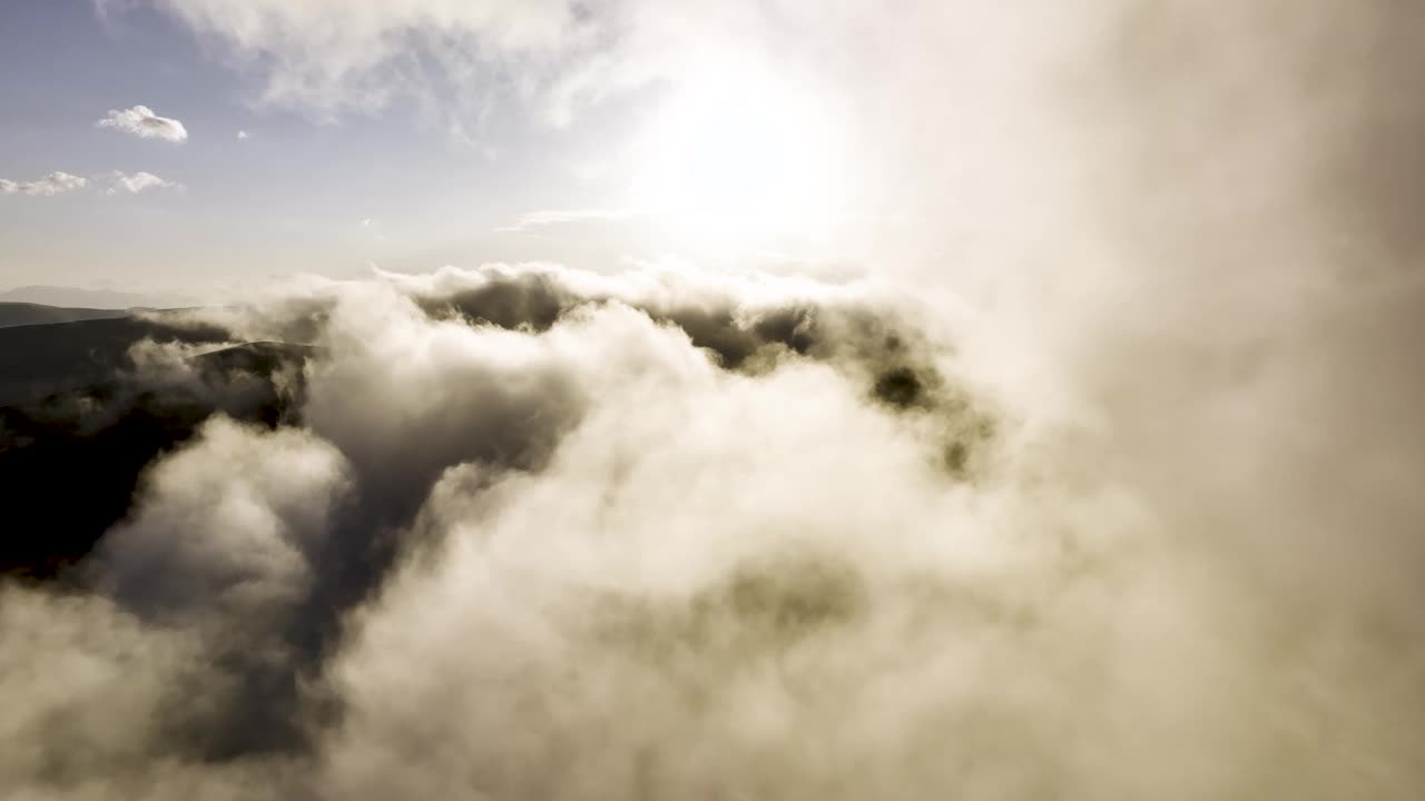 鸟瞰图飞越天空美丽的阳光云景。令人惊叹的白色蓬松的云彩在天空中轻柔地移动，太阳在云层上闪耀着美丽的光线和镜头光晕视频素材