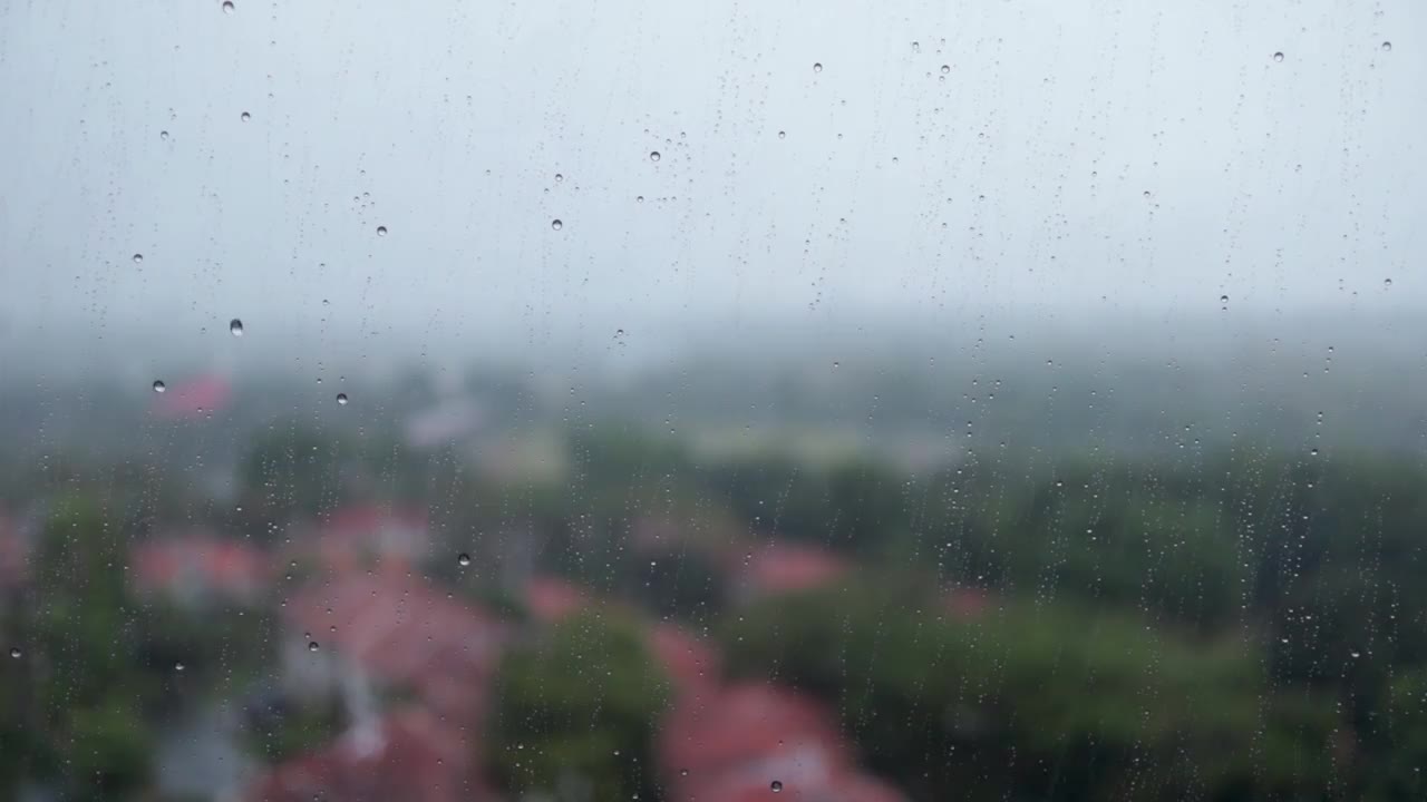 雨滴落在窗户表面的玻璃上，以丘陵自然景观为背景。外面的大雨和室内公寓的景色。视频素材