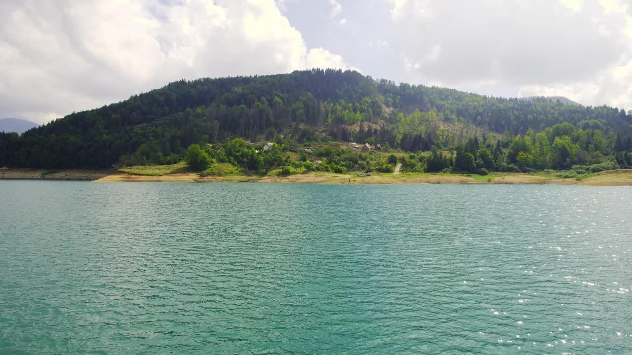 在枣湾的阴天，无人机在水面上飞向树木繁茂的小山视频素材