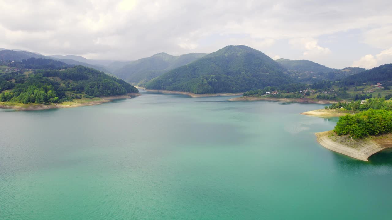 美丽的风景，绿松石般的湖泊，树木繁茂的山丘环绕在云中视频素材