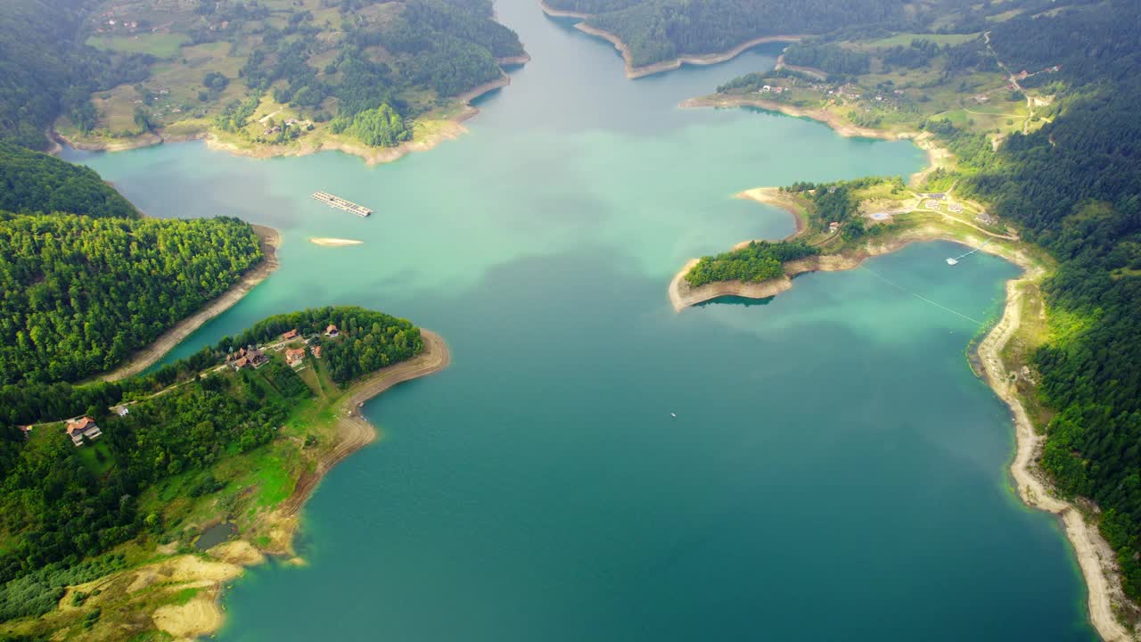 鸟瞰图的海岸大的蓝色湖泊与少数房屋和林地在Zaovine视频素材