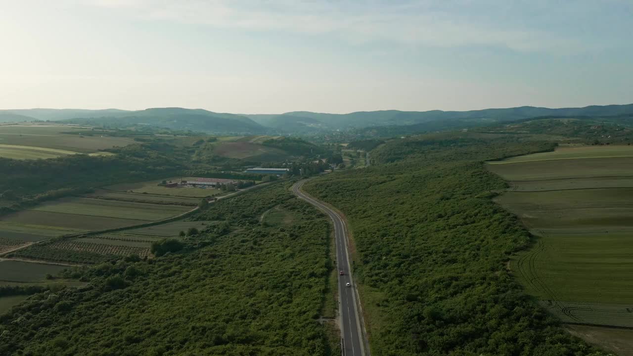 鸟瞰图，一条道路被绿色植物包围，背景是山脉的剪影视频素材