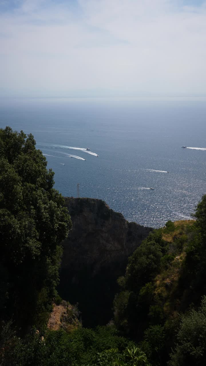 从阿马尔菲海岸的山脉到以美丽的海景和夏日地平线为背景在地中海航行的船只和游艇的垂直景观视频素材