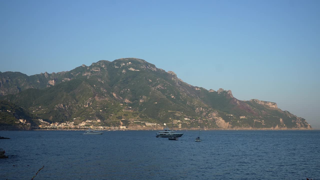 从旅游渡轮的游艇和船只停泊在阿马尔菲海岸。在阳光明媚的夏日，从船上俯瞰阿马尔菲海岸山坡上的联排别墅视频素材