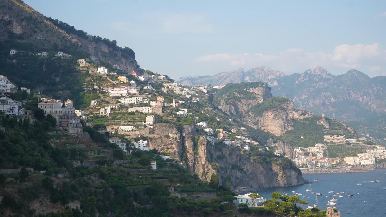 在阳光明媚的夏日，美丽的海景和蓝天，阿马尔菲海岸的村庄，山上的房子，舒适的海滩和蓝色的大海。视频素材