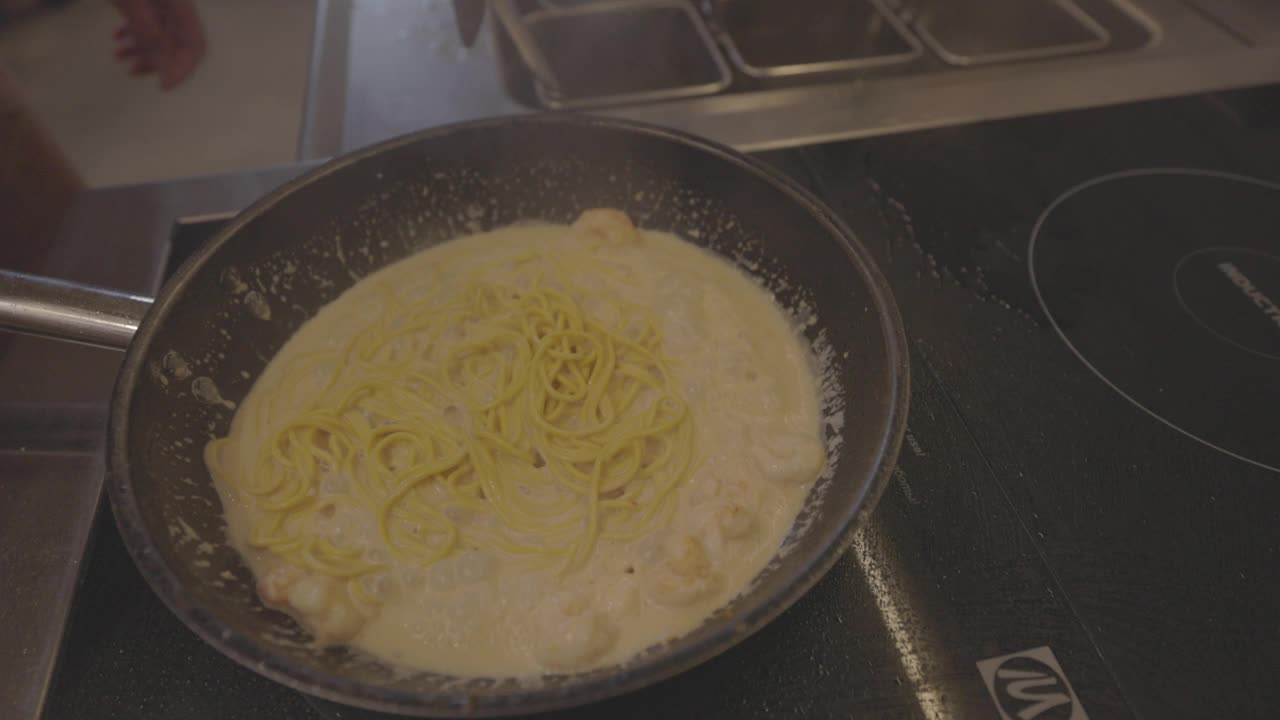 意大利面食烹饪过程。煮熟的意大利面与酱汁和配料混合在热锅里。意大利菜，传统食谱。慢动作120fps, ProRes 422, 10位，未分级的C-LOG视频视频素材