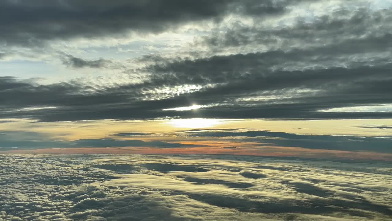 从一架向西飞行12000米高空的喷气式飞机机舱拍摄的日落时，令人惊叹的多云天空。飞行员的真实视角视频素材